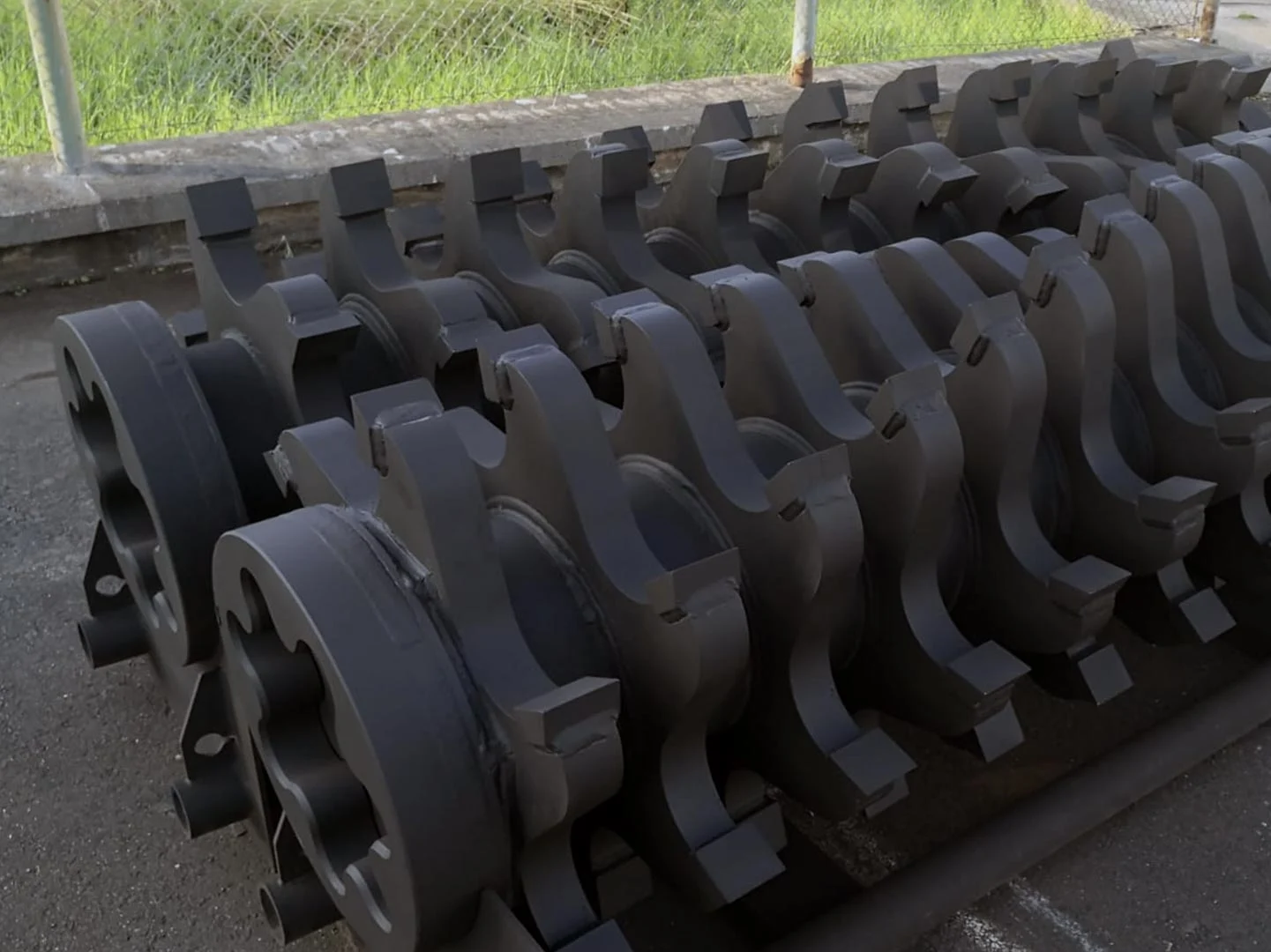 Multiple robust shredder cams and knife blocks, components designed for ARJES TITAN 900-950 rotor shafts, neatly arranged outdoors.