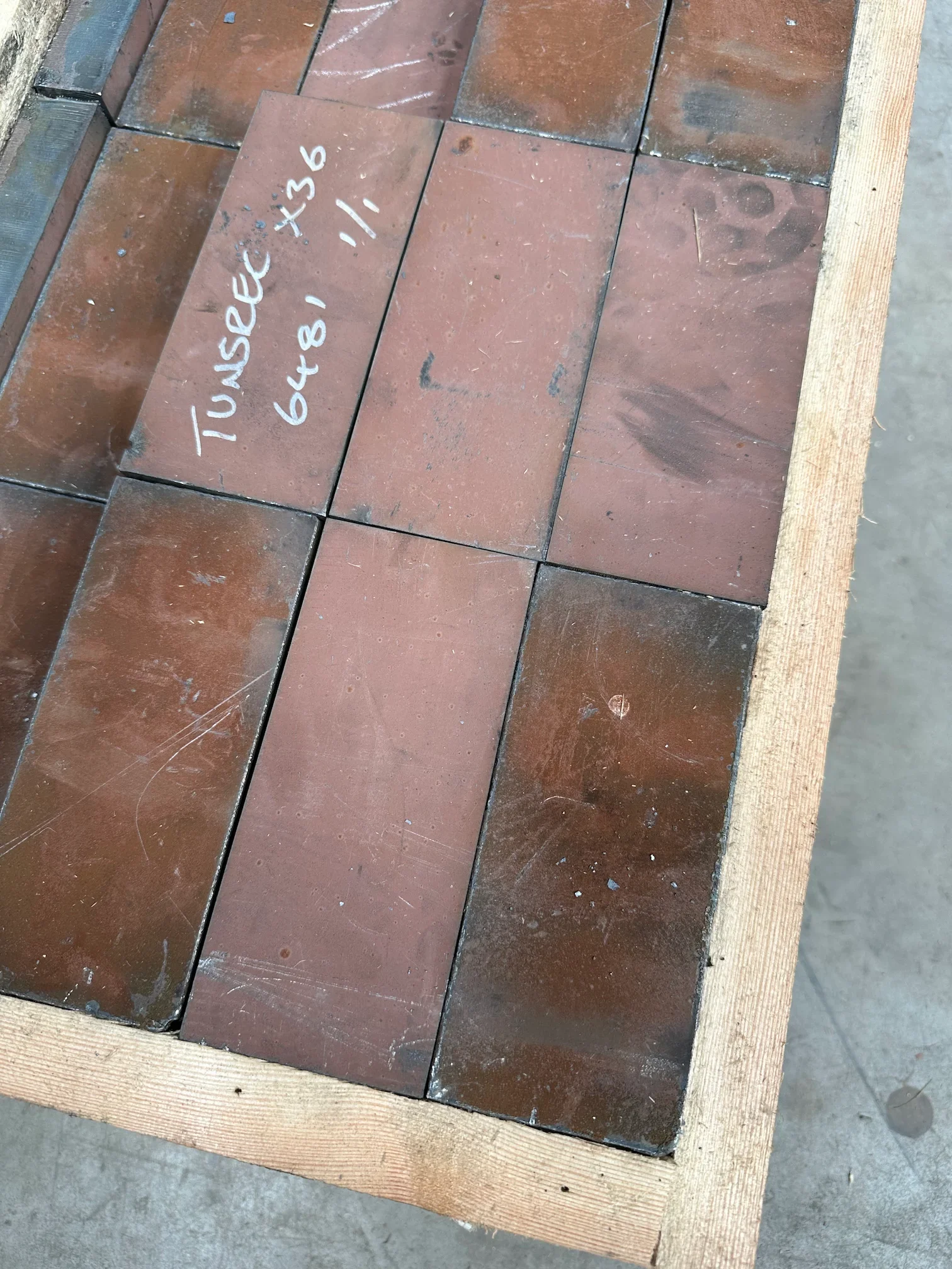 Close-up view of multiple new Hardox 500 knife blocks, 160x70x30mm, stacked in a wooden crate, ready for ARJES Impaktor 250 and Compaktor 300 V22 shaft replacement.