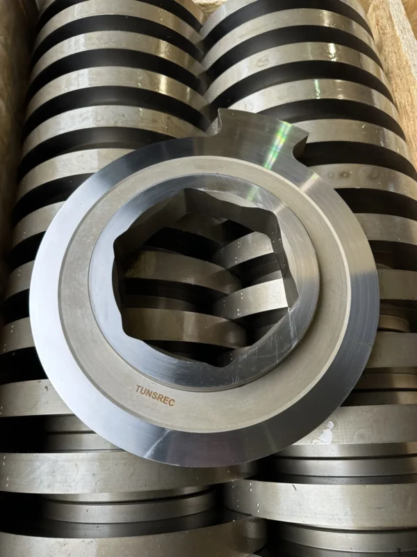 Stack of metallic UNTHA RS shredder cutter units, featuring a prominent TUNSREC part in the foreground, ready for industrial use.